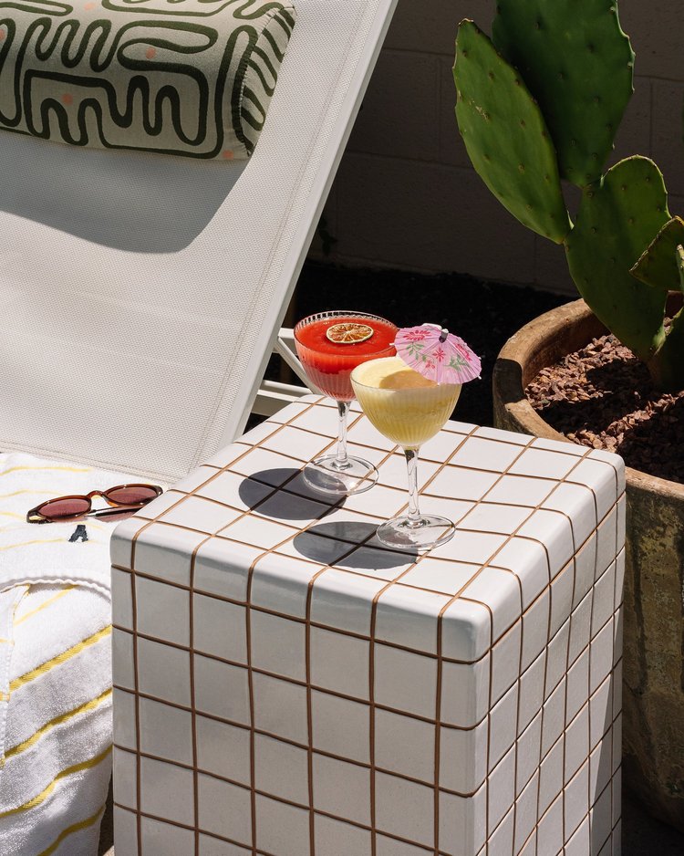 Cocktails on a tiled side table on a sunny poolside patio