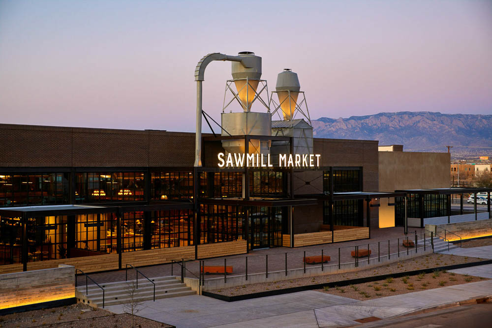 Sawmill Market food hall at dusk with the Sandia Mountains behind it