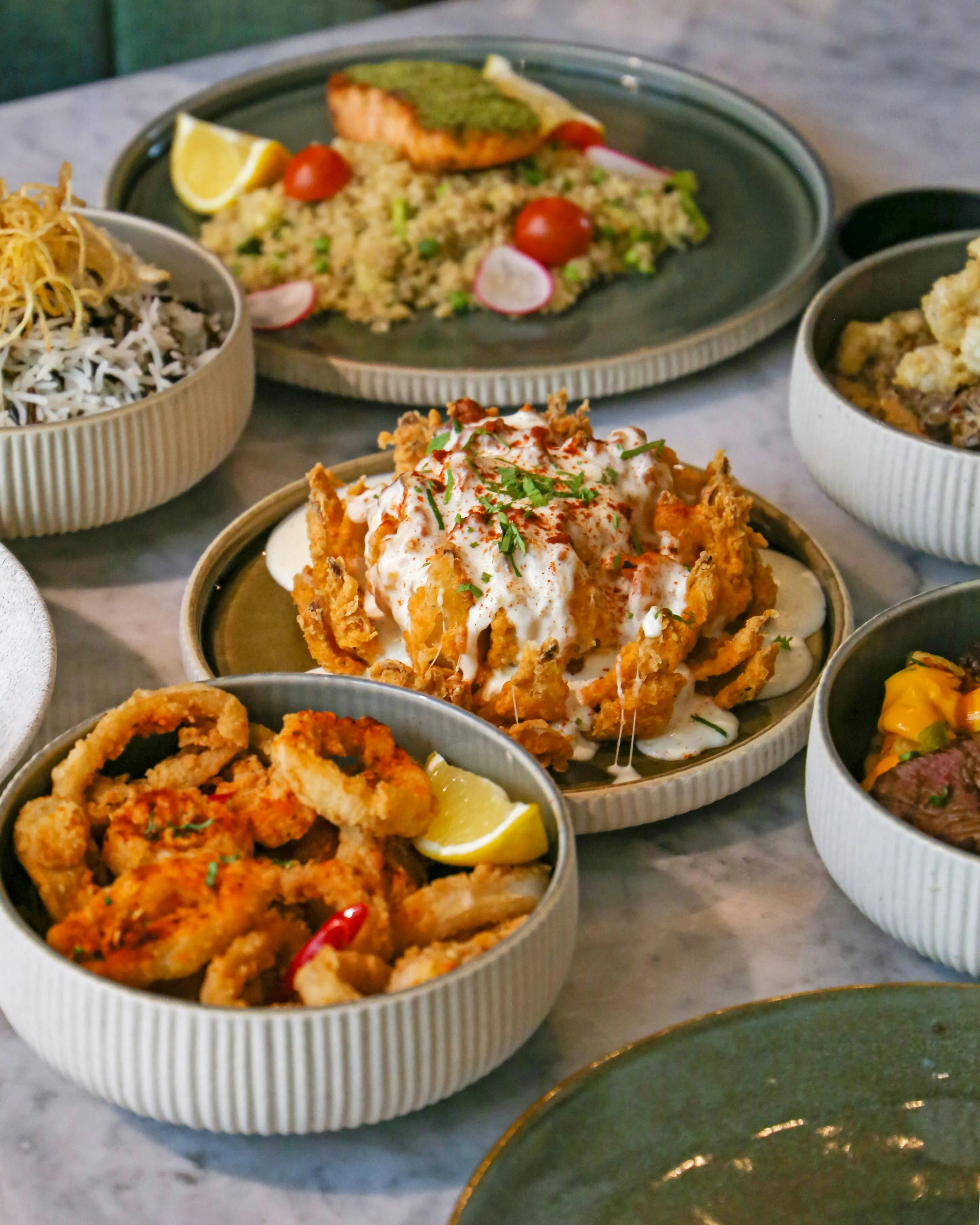 Shared plates of seafood, grains, and salads on a restaurant table