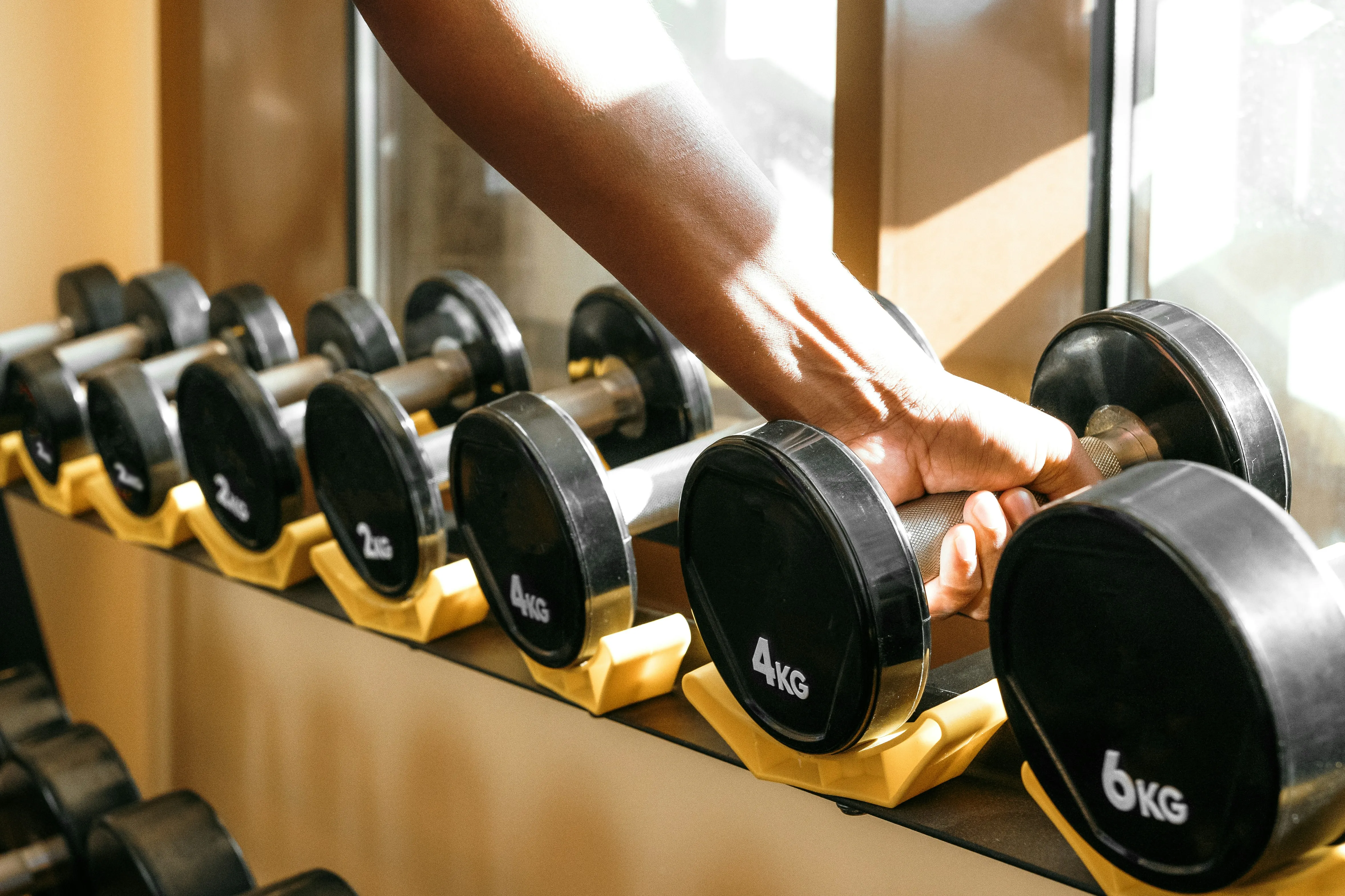Resident picking up a dumbbell from a rack in the private gym